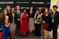 A group of School of Liberal Arts alumni pose in front of a Liberal Arts banner.